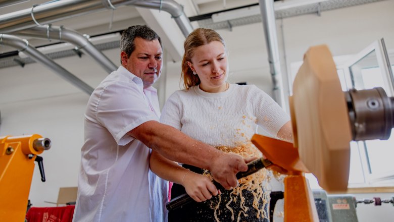Ein Mann und eine Frau arbeiten gemeinsam an einer Drechselmaschine.
