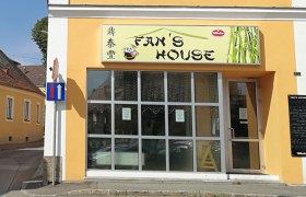 Außenansicht eines Restaurants namens Fan's House mit gelber Fassade und großen Fenstern.