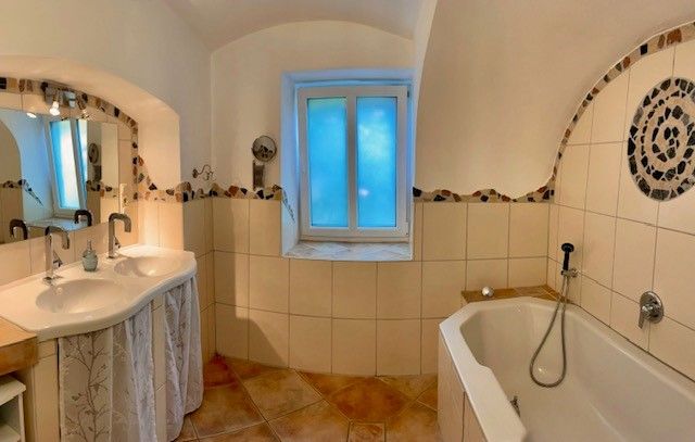 Ein Badezimmer mit Doppelwaschbecken, Badewanne und gefliestem Boden.