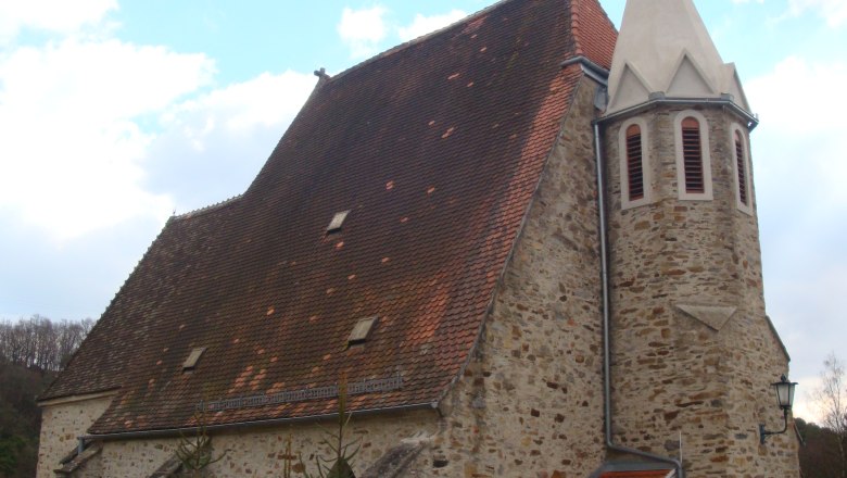 Pöbring parish church with steep roof and tower against a blue sky.