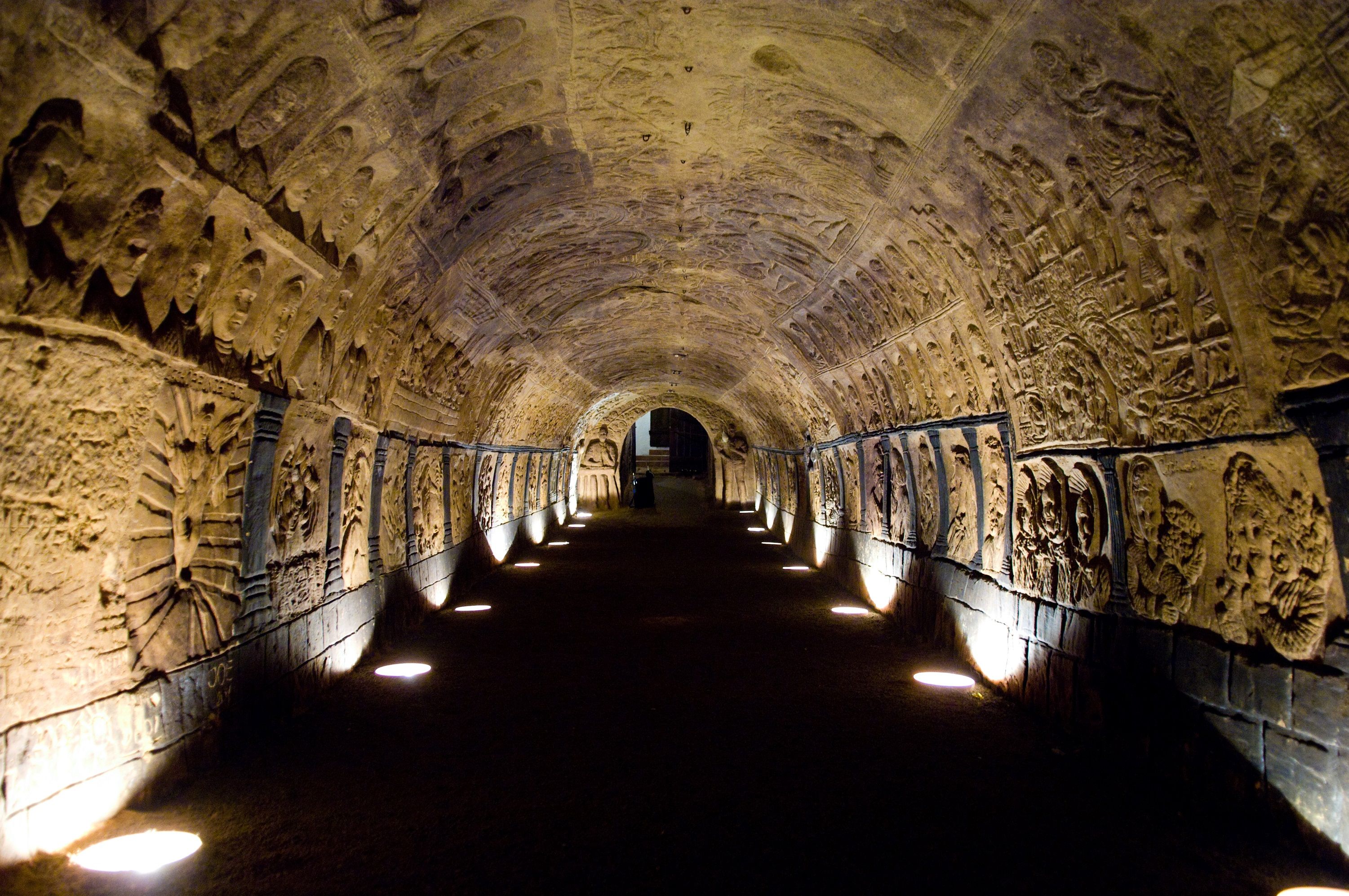 Ein beleuchteter, mit Reliefs verzierter Tunnel in einem historischen Keller.