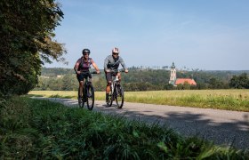 Radfahrer genießen die frische Luft und die malerische Landschaft entlang des Kamptal Radwegs. Umgeben von sanften Hügeln und üppigen Wiesen, strahlt die Umgebung eine einladende Ruhe aus, die zum Verweilen einlädt.