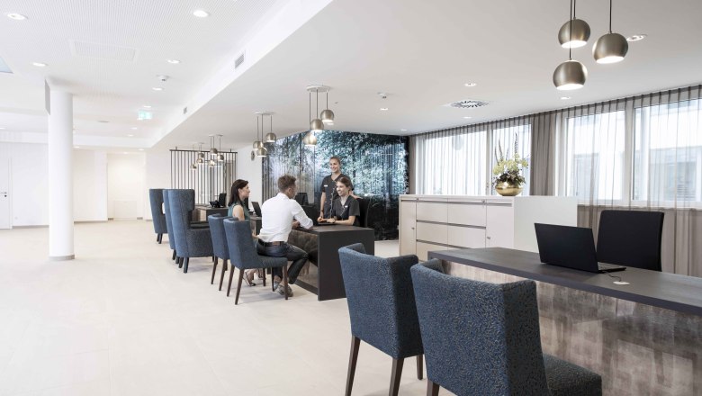 Moderne Rezeption mit Menschen, die an einem Tisch sitzen und sprechen.