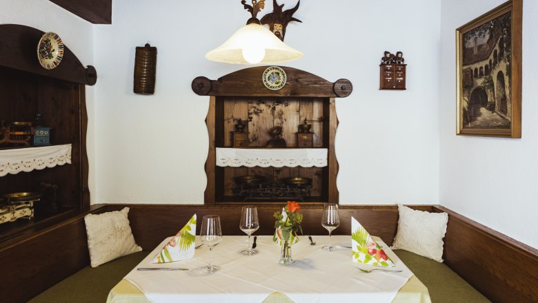 Gemütliche Sitzecke in einem Restaurant mit Holzmöbeln, dekorativen Details und gedecktem Tisch.