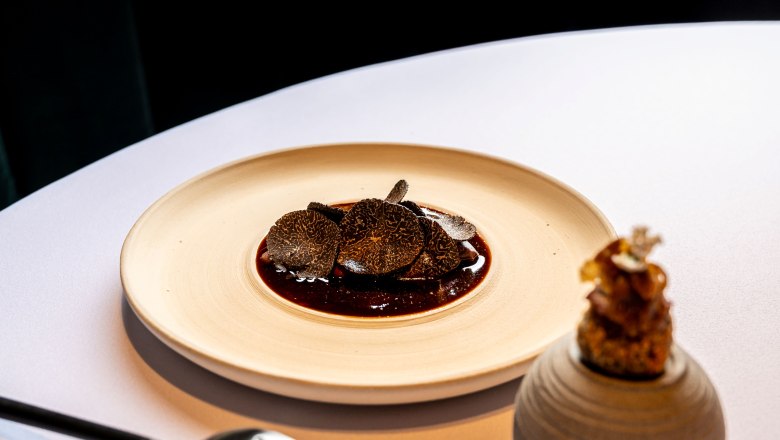 Ein Gourmetgericht mit Tr&uuml;ffelscheiben auf einem Teller, daneben ein dekoratives Element.