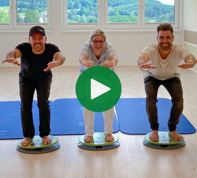 3 Personen auf einem Gymnastikbrett mit Blick in die Kamera
