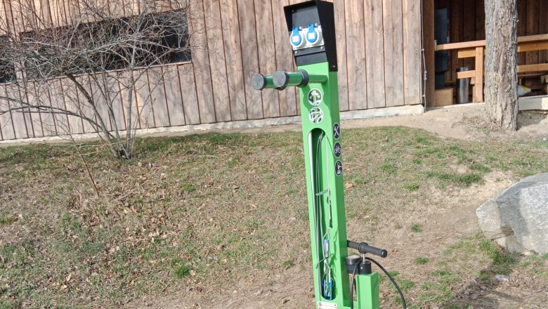Green e-bike charging stations in front of a wooden building.