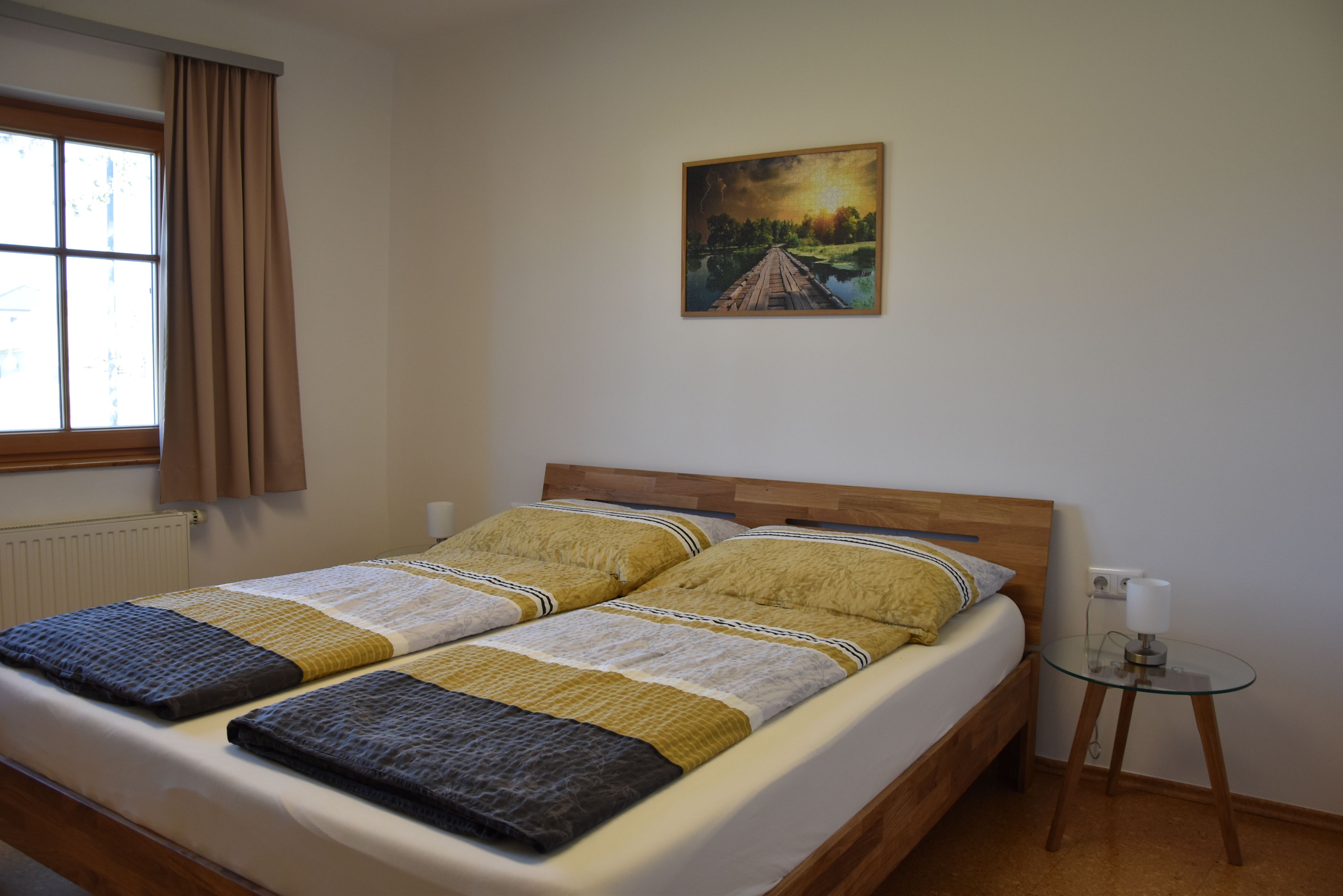 Schlafzimmer mit Doppelbett, Fenster mit Verdunkelungsvorhang, Nachttisch und Schrank.