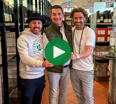 3 Personen, die mit Weingläsern in der Vinothek zusammenstoßen