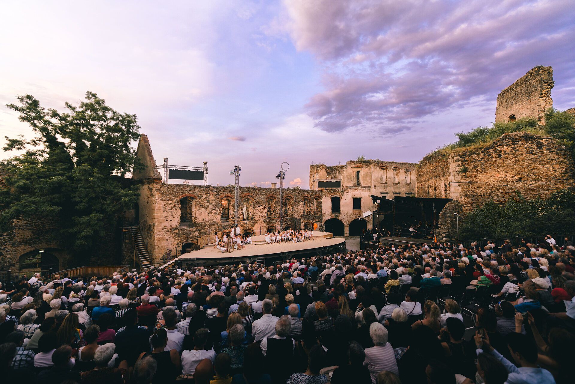 In der beeindruckenden Kulisse der Burg Gars versammeln sich zahlreiche Besucher, um ein unvergessliches Theaterfest zu erleben. Die altehrwürdigen Mauern und der malerische Himmel schaffen eine magische Atmosphäre, die die Herzen der Zuschauer berührt. Hier wird Kultur lebendig und die Schönheit des Moments gefeiert.