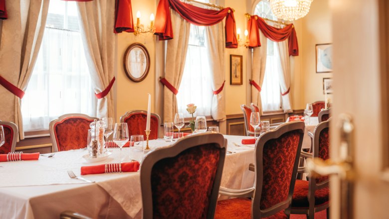 Elegantes Restaurant mit gedecktem Tisch, roten St&uuml;hlen und Kronleuchter.