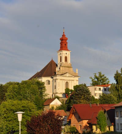 Wallfahrtskirche auf einem H&uuml;gel mit roten D&auml;chern und B&auml;umen im Vordergrund.