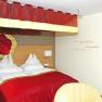 Gemütliches Hotelzimmer mit rotem Baldachin und Rosenmotiv an der Wand.
