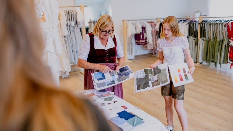 Zwei Frauen betrachten Stoffmuster in einem Trachtenmodegeschäft.
