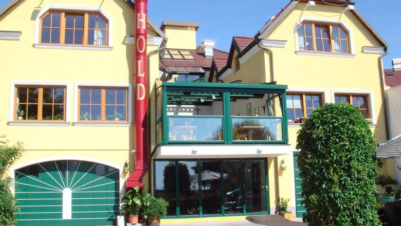 Gelbes Gebäude mit rotem Kamin und Schriftzug 'HOLD'.