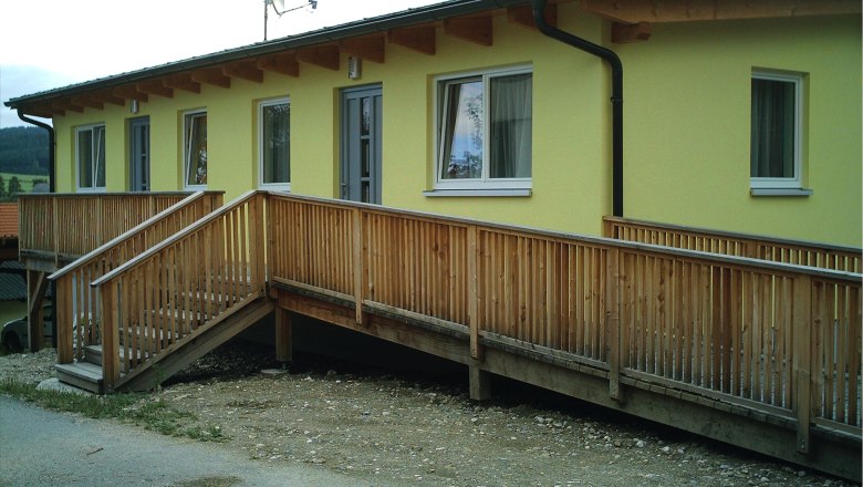 Gasthof Christiane Winter, © Gasthof Christiane Winter Gelbes Gebäude mit Holzrampe und Fenstern.