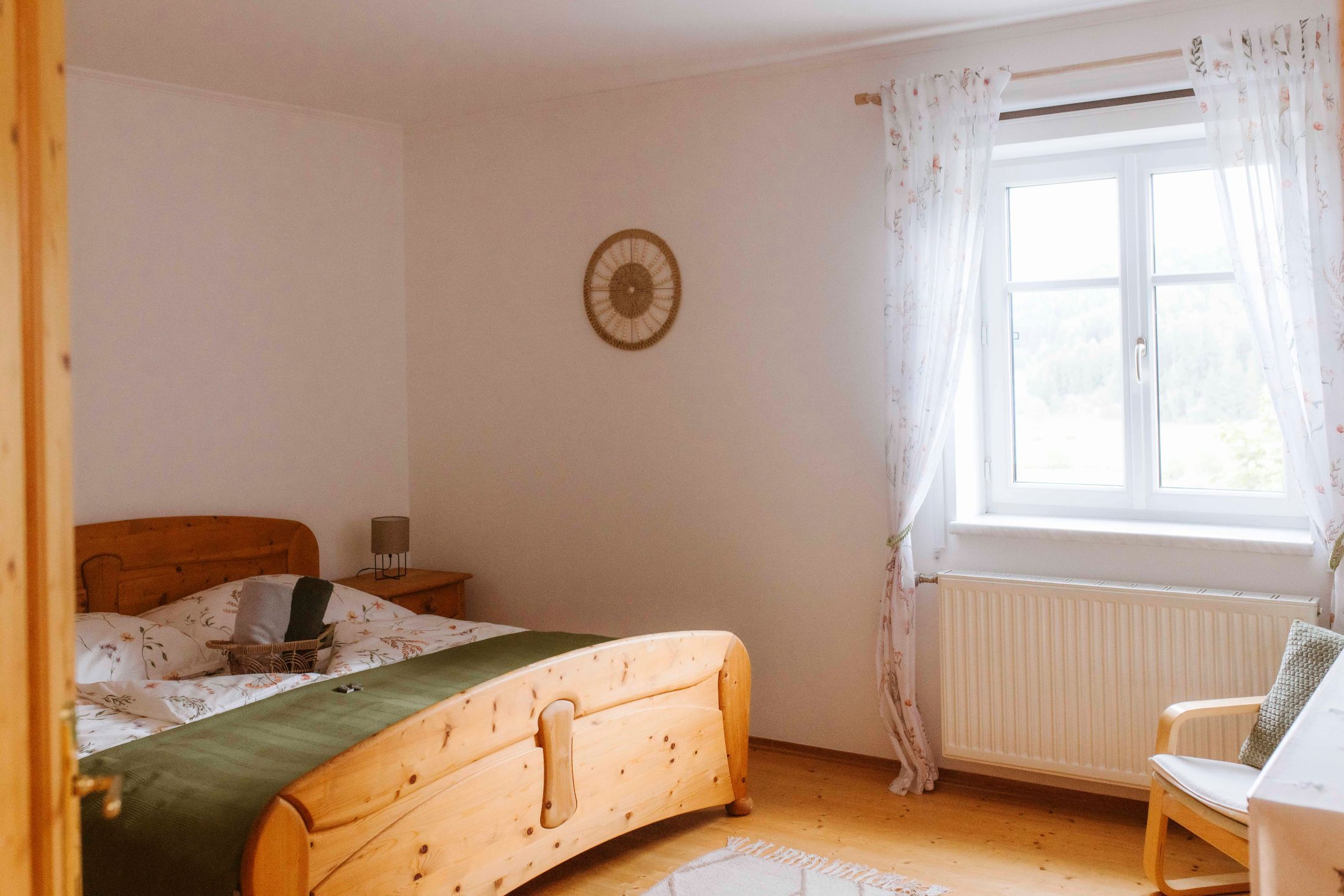 Gemütliches Doppelzimmer mit Holzmöbeln und Fenster mit Vorhängen.