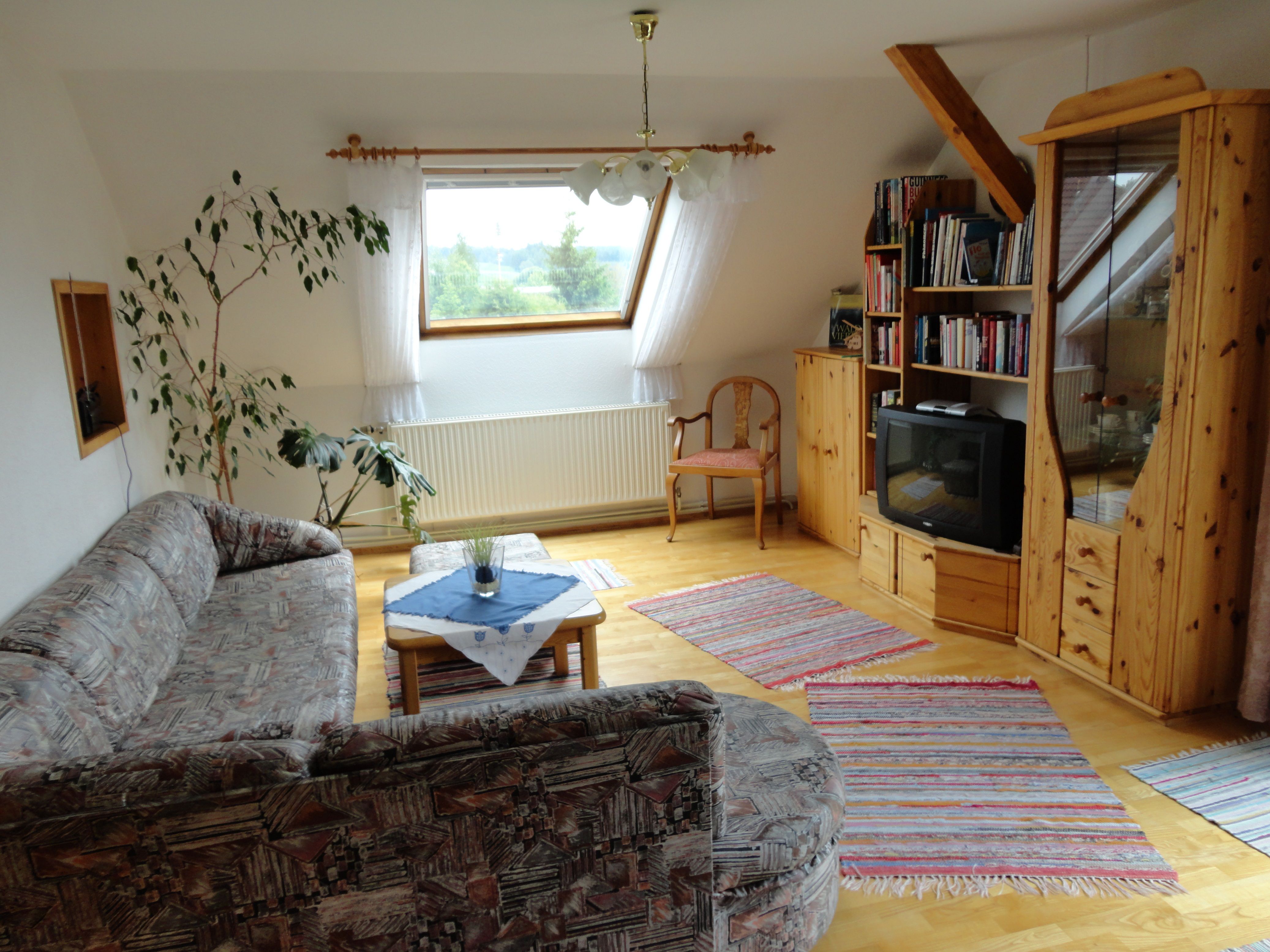 Gemütliches Wohnzimmer mit Sofa, Holzmöbeln und Fernseher.