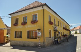 Yellow building with the inscription 'Gasthof Speneder', decorated with flowers.