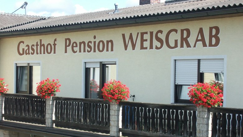 Fassade der Pension Weisgrab mit Blumenkästen auf dem Balkon.