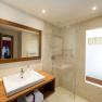 Modern bathroom with wooden details, washbasin, mirror and glass shower.