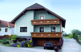 Ein zweistöckiges Haus mit Holzbalkon und Garten.