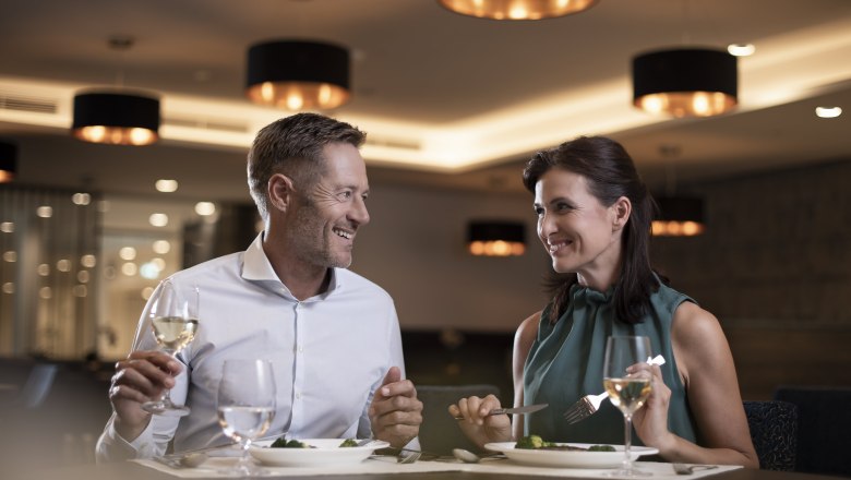 A couple is sitting in an elegant restaurant enjoying a dinner with wine.
