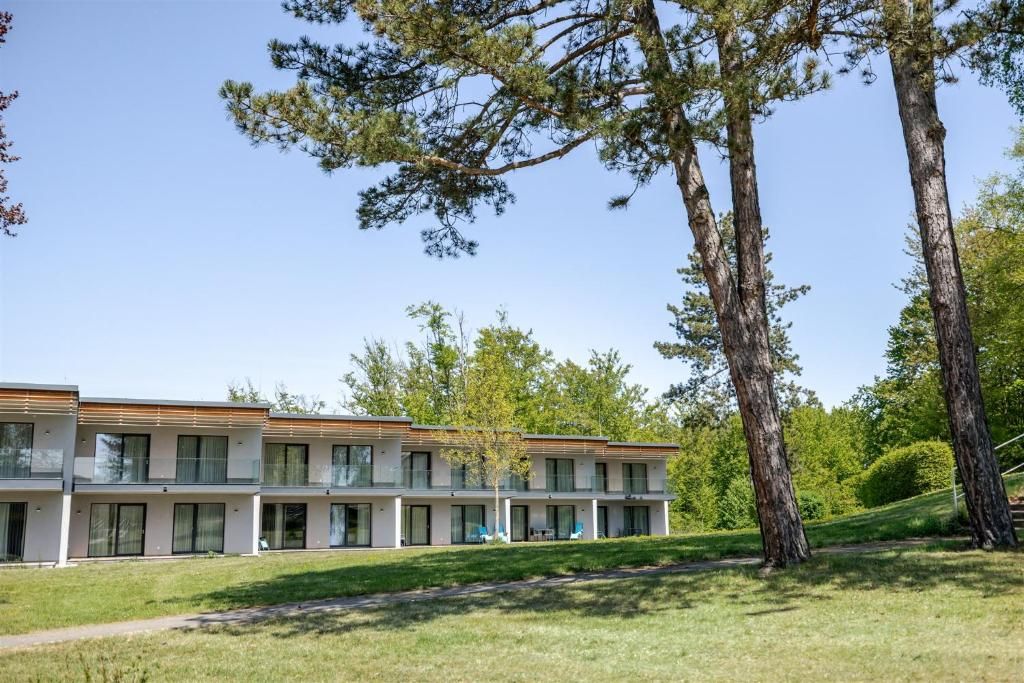 Hotel Ottenstein – Das Wohlfühlhotel: modernes Hotelgebäude mit Balkonfront in grüner Parklandschaft und hohen Bäumen.