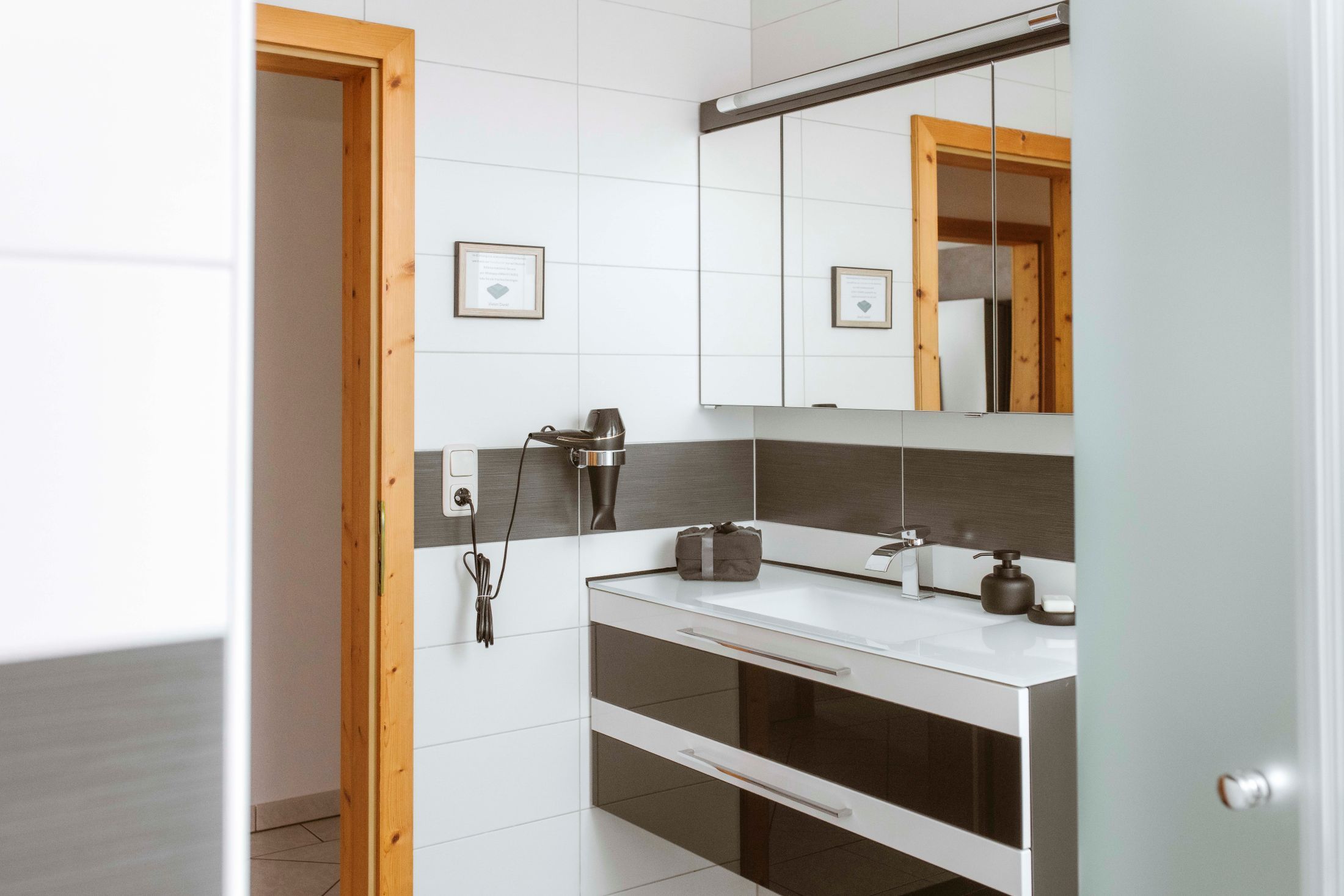 Modernes Badezimmer mit Spiegel, Waschbecken und Haartrockner an der Wand.