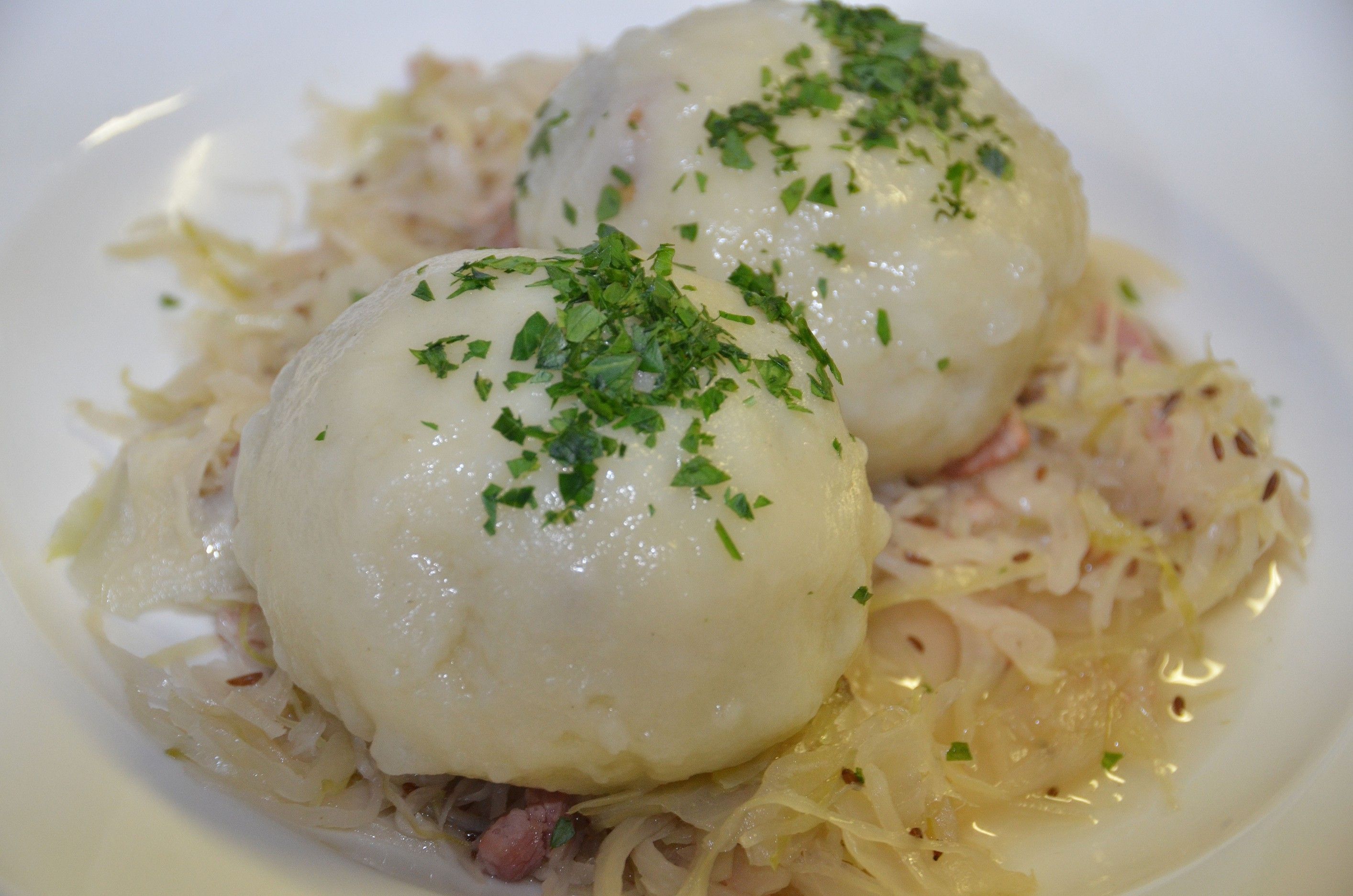 Zwei Grammelknödel auf Sauerkraut, garniert mit Petersilie.