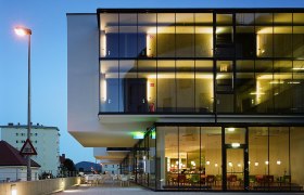 Modernes Hotelgebäude mit Glasfassade bei Dämmerung.