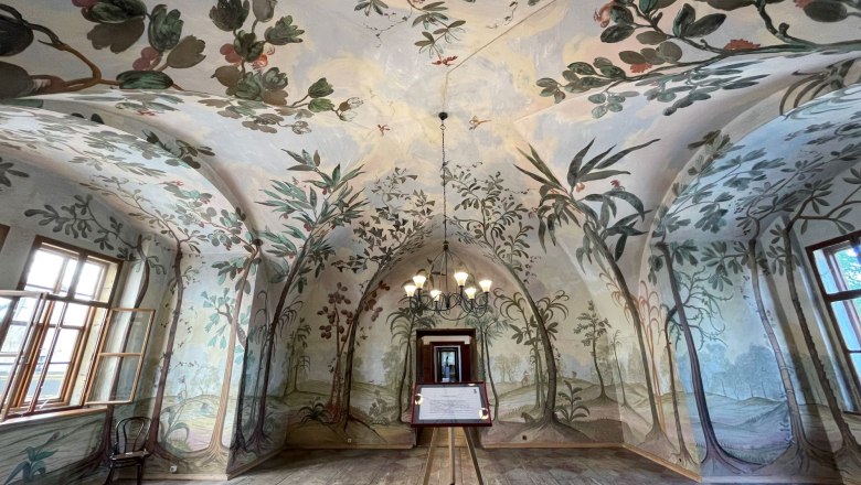 An artistically painted room with a vaulted ceiling and floral motifs on the walls.