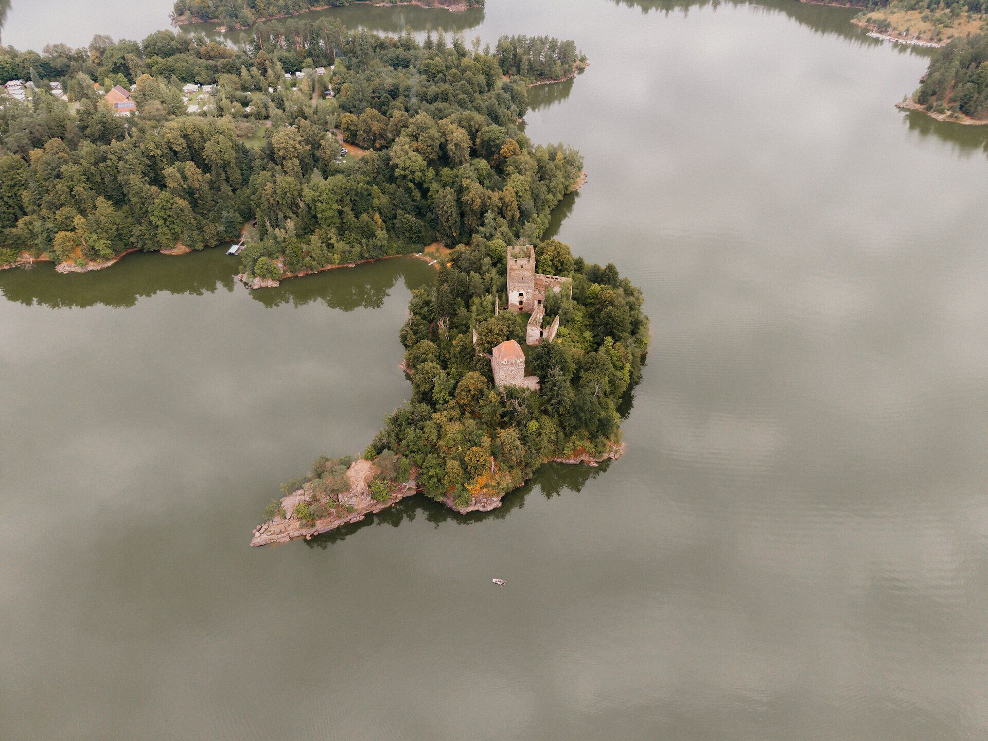 Luftaufnahme der Ruine Lichtenfels auf einer bewaldeten Halbinsel im Stausee Ottenstein im Waldviertel, umgeben von ruhigem Wasser und dichtem Grün.