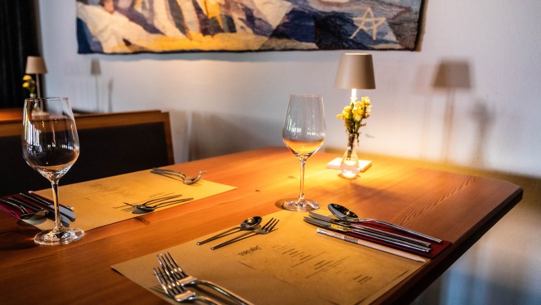 Eleganter Tisch in einem Restaurant mit Weingläsern, Besteck und Blumen.