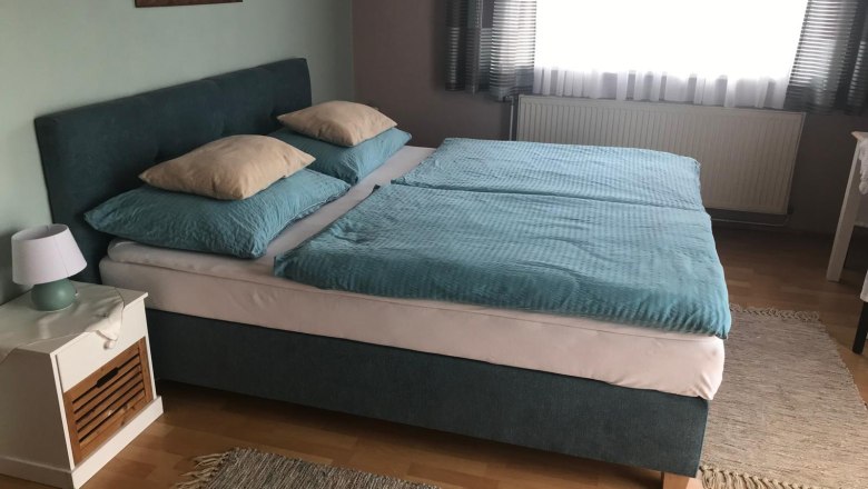 Schlafzimmer mit Doppelbett, blauer Bettwäsche und Nachttisch mit Lampe.