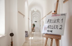 Ein heller Flur mit einem Schild auf einer Staffelei, das auf Atelier 1 und Atelier 2 hinweist.