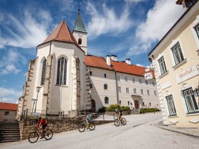 Die sanften H&uuml;gel laden zu einem unvergesslichen Abenteuer ein, w&auml;hrend die malerische Architektur der Umgebung eine harmonische Kulisse bietet. Radfahrer gleiten die Stra&szlig;e hinauf, um die atemberaubenden Ausblicke auf die umliegende Natur zu genie&szlig;en. Hier, wo Tradition und Natur aufeinandertreffen, wird jeder Moment zum Erlebnis.