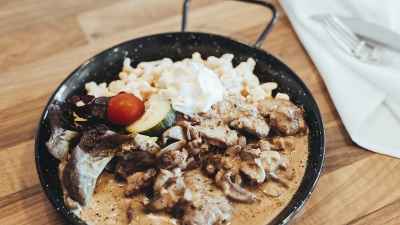 Ein Gericht in einer Pfanne mit Fleisch, Sp&auml;tzle, Sahne und Gem&uuml;se.