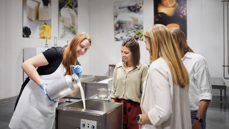 A woman pours milk into a container while three people look on.
