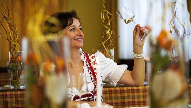 Woman in traditional dress holding a wine glass in a restaurant.