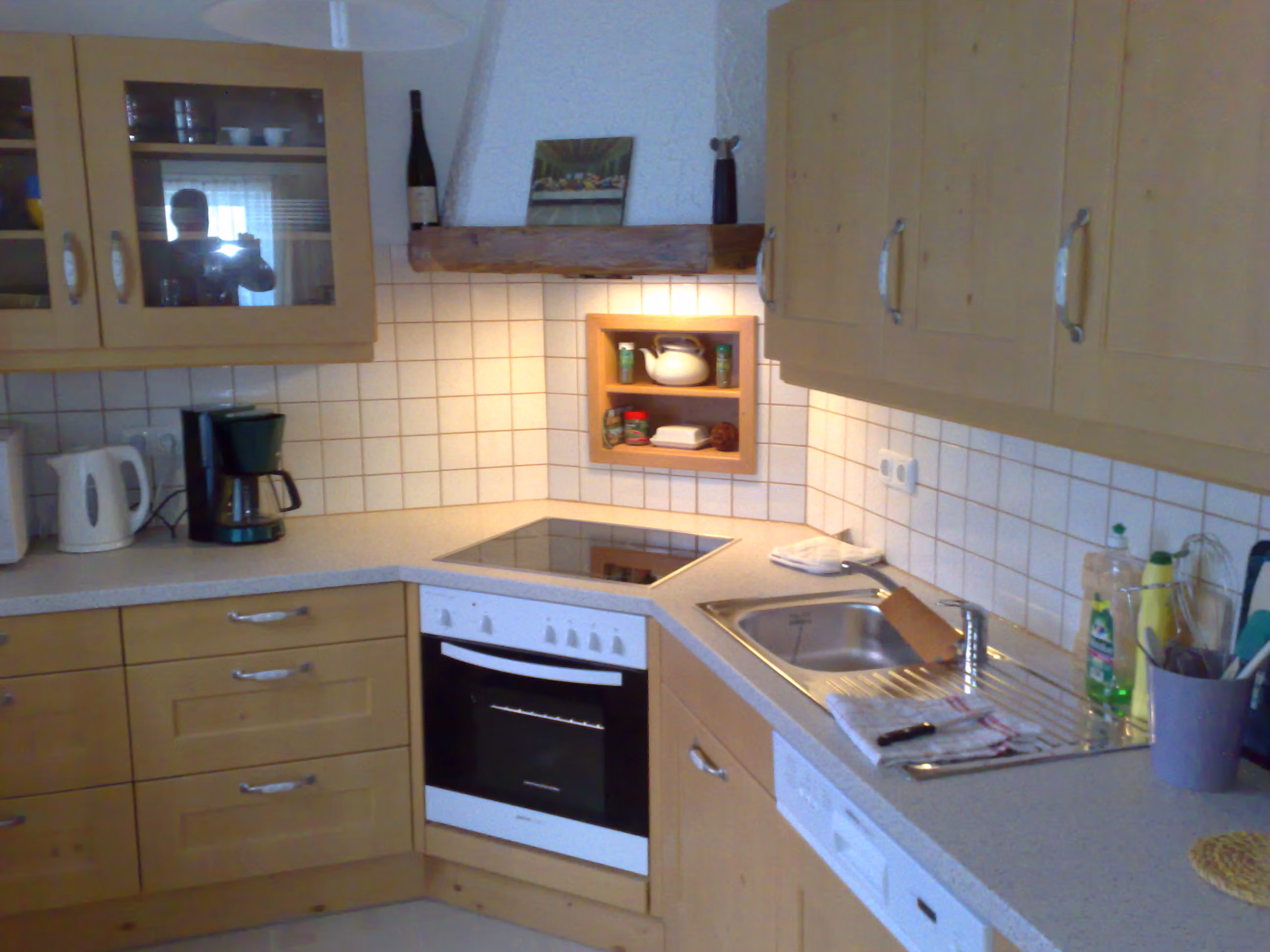 Küche mit Holzschränken, Herd, Spüle und Kaffeemaschine.