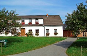 Ein traditionelles Bauernhaus mit Blumen an den Fenstern und einem gepflegten Garten.