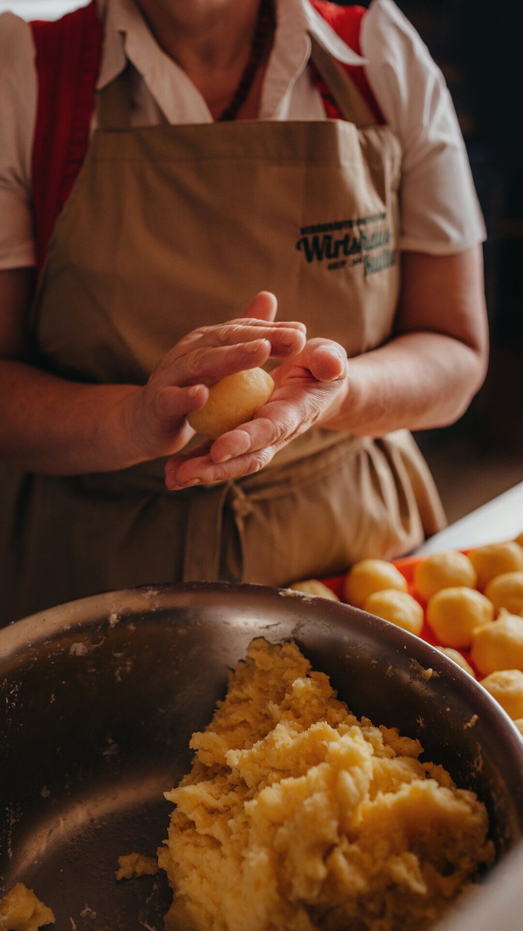 In der Wirtshausbrennerei Krenn wird mit viel Liebe und handwerklichem Geschick ein traditionelles Gericht zubereitet. Die Köchin formt sorgfältig Kartoffelknödel, die bald auf den Tellern der Gäste landen werden. Hier im Yspertal vereinen sich Genuss und regionale Küche in perfekter Harmonie.