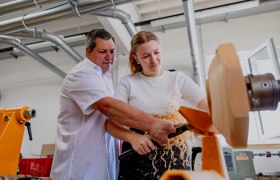 Ein Mann und eine Frau arbeiten gemeinsam an einer Drechselmaschine.