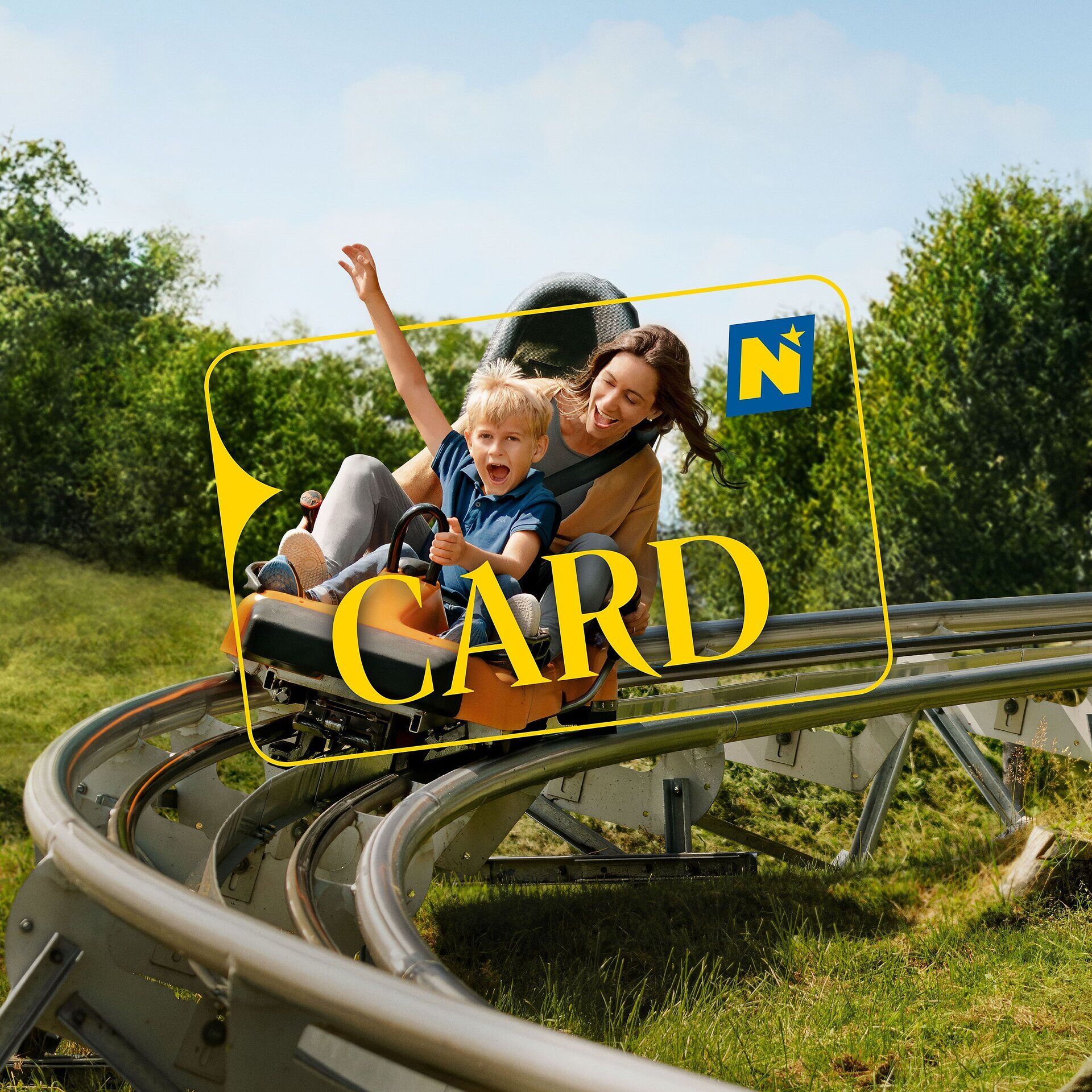 Ein fröhliches Lachen erfüllt die Luft, während ein Kind und eine Begleitperson in einem rasanten Fahrvergnügen auf einer Sommerrodelbahn die kurvenreiche Strecke hinunter sausen. Umgeben von üppigem Grün und strahlend blauem Himmel, erleben sie einen unvergesslichen Tag voller Abenteuer und Freude.