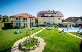 Gartenanlage mit gelben Geb&auml;uden und Liegest&uuml;hlen bei sonnigem Wetter.