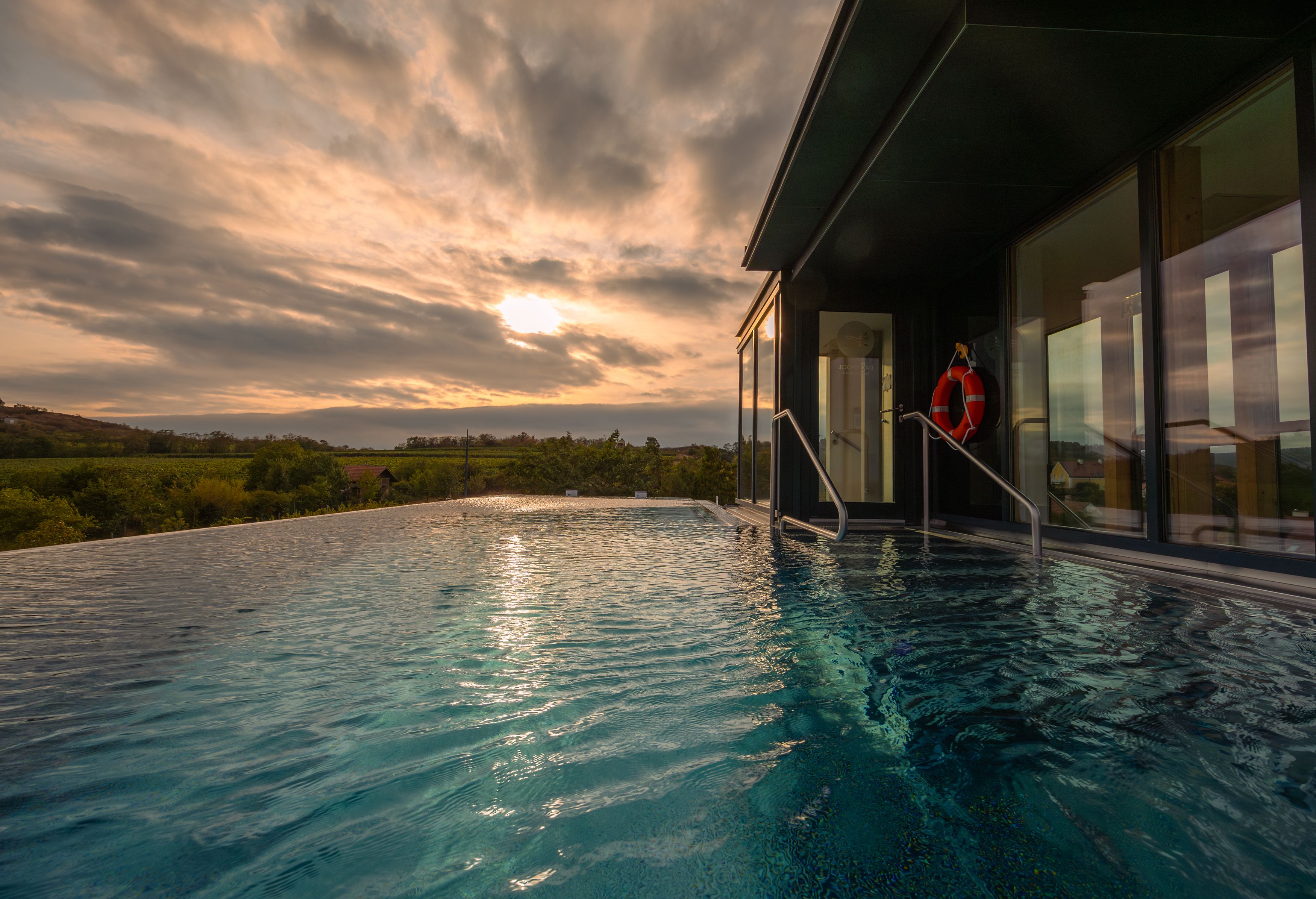 Infinity-Pool mit Blick auf die Landschaft bei Sonnenuntergang.