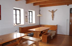 Rustikaler Raum mit Holzmöbeln, Holzbalkendecke und Wanddekoration.