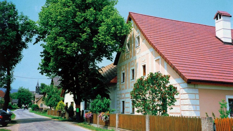Mostgwölb Müllauer, © Mostgwölb Müllauer Straße mit traditionellen Häusern und Bäumen in einer ländlichen Umgebung.