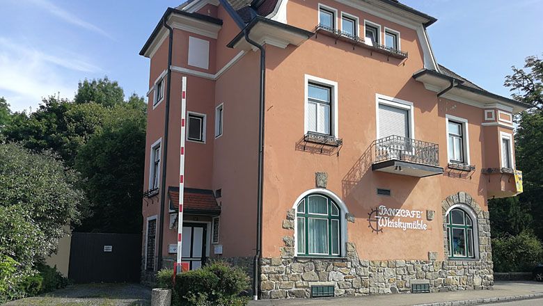 Ein zweistöckiges Gebäude mit der Aufschrift 'Tanzcafé Whiskymühle'.